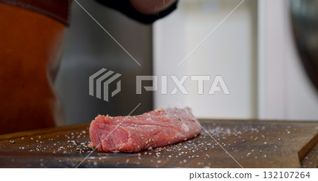 Seasoning Raw Meat on Preparation Table. Chef preparing Meat Seasoning Raw Meat on Preparation Table. Chef preparing Meat 132107264