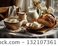 Wholesome dairy meal with bread loaf, soft cheese, milk pitcher, and rustic table setting in cozy interior 132107361