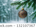 Close-up of glittery Christmas bauble hanging from snow-covered pine branch with falling snowflakes and blurred winter forest background with copy space 132107367
