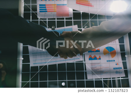 Business people shaking hands in office. Two business partners shaking hands after signing a contract in office. Business people shaking hands in office. Two business partners shaking hands after signing a contract in office. 132107823