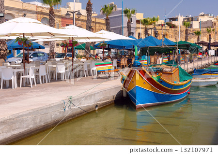 Colorful luzzu boat on Marsaxlokk promenade, Malta Colorful luzzu boat on Marsaxlokk promenade, Malta 132107971