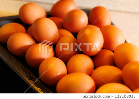 Fresh brown eggs gathered in a rustic tray ready for cooking or baking at a cozy kitchen Fresh brown eggs gathered in a rustic tray ready for cooking or baking at a cozy kitchen 132108033