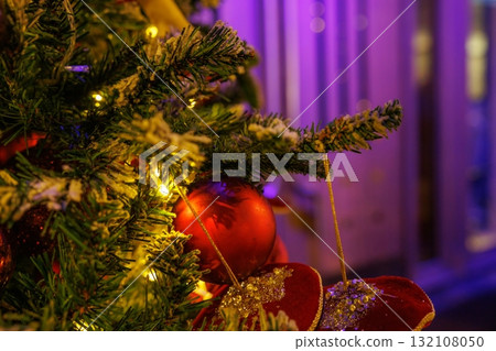 Bright Christmas tree decorated with ornaments and lights during evening 132108050