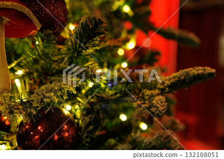 Festive Christmas tree adorned with lights and ornaments, creating a warm holiday atmosphere 132108051