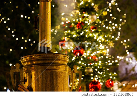 Warm glow from a decorative heater near a beautifully lit Christmas tree with festive ornaments at night 132108065