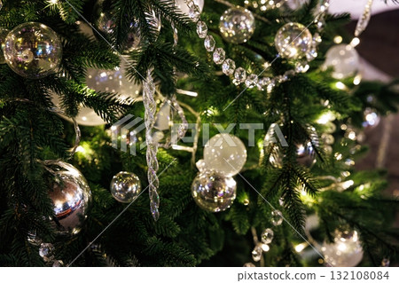 Sparkling ornaments and lights decorate a festive Christmas tree in a cozy indoor setting during the holiday season Sparkling ornaments and lights decorate a festive Christmas tree in a cozy indoor setting during the holiday season 132108084