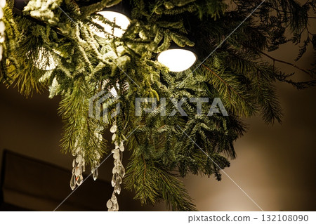 Decorative greenery enhances warm lighting in a cozy winter setting with hanging icicle-like ornaments 132108090