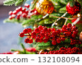 Festive holiday decorations showcasing bright red berries and sparkling ornaments on a Christmas tree 132108094