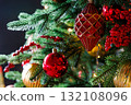 Festive decorations on a Christmas tree adorned with red and gold ornaments glowing in soft light 132108096