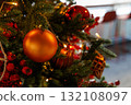 Brightly decorated Christmas tree adorned with shiny ornaments and warm lights in a cozy indoor setting 132108097