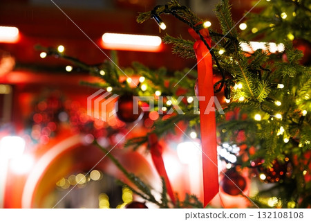 Christmas tree adorned with red ribbons and ornaments in a festive market setting during evening hours Christmas tree adorned with red ribbons and ornaments in a festive market setting during evening hours 132108108