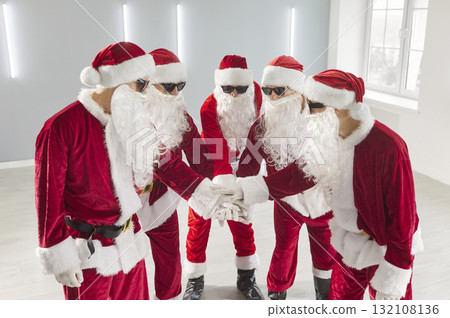 People in Santa Claus costumes putting their arms in a pile celebrating New Year or Christmas People in Santa Claus costumes putting their arms in a pile celebrating New Year or Christmas 132108136