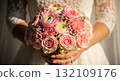 A hyper-realistic, high-detail close-up photograph of a bride's hands gently holding a gorgeous wedding bouquet filled with pink Roses, Ranunculus, and small Carnations 132109176