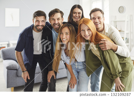 Group portrait of happy millennial friends or colleagues smiling and hugging while standing together Group portrait of happy millennial friends or colleagues smiling and hugging while standing together 132109287