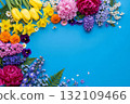 Beautiful floral frame on a vibrant blue background, featuring a colorful assortment of spring flowers 132109466