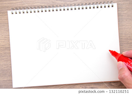 A hand holding a notebook and a red permanent marker 132110251