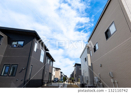 A streetscape of modern detached houses lined up under the blue sky 132110742
