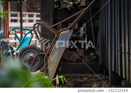 一輛舊手推車靠在倉庫的牆上 一輛舊手推車靠在倉庫的牆上 132112324