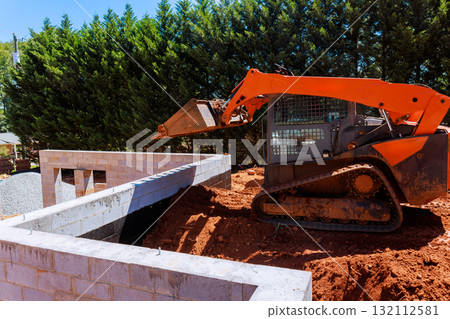 Heavy machinery is actively moving dirt at construction site where foundation 132112581