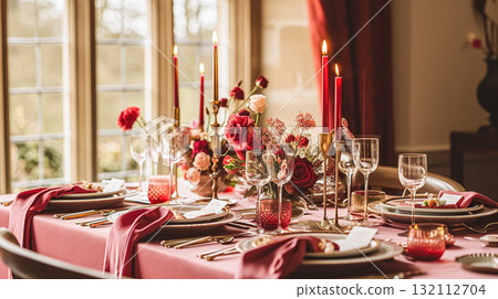 Festive table setting with cutlery, candles and beautiful red flowers in a vase. 132112704