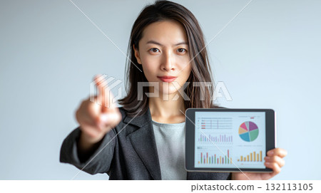 Confident businesswoman holding tablet with analytics dashboard and pointing forward, concept of data and strategy 132113105