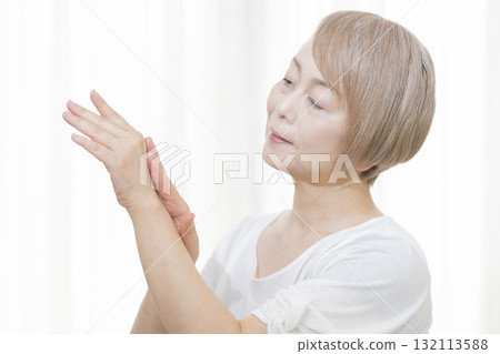 老年婦女塗抹乳霜來擦乾手和手指 老年婦女塗抹乳霜來擦乾手和手指 132113588