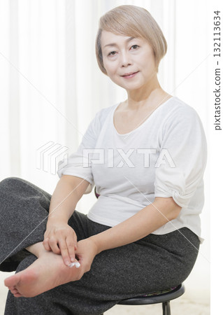 Senior woman applying cream to dry heels 132113634
