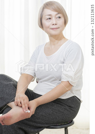 Senior woman applying cream to dry heels 132113635