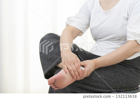 Senior woman applying cream to dry heels 132113638