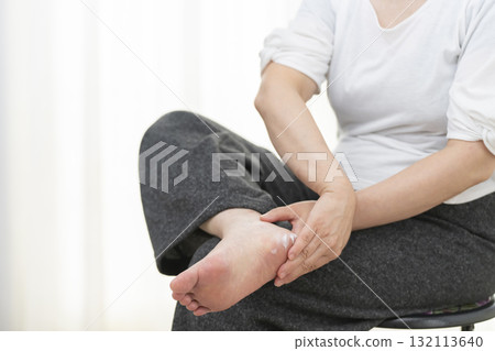 Senior woman applying cream to dry heels 132113640