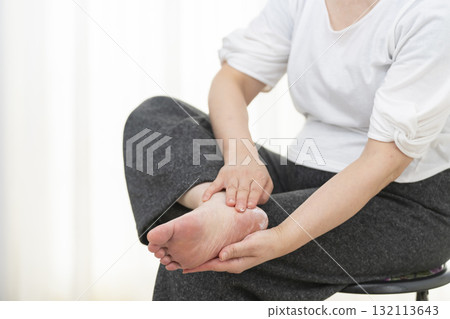 Senior woman applying cream to dry heels 132113643