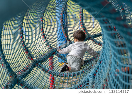 Children playing in a mesh tunnel in the park Children playing in a mesh tunnel in the park 132114317