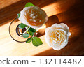 Yellow beautiful blooming rose in glass vase under window light on wooden table. 132114482