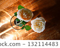 Yellow beautiful blooming rose in glass vase under window light on wooden table. 132114483