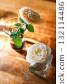 Yellow beautiful blooming rose in glass vase under window light on wooden table. 132114486
