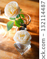 Yellow beautiful blooming rose in glass vase under window light on wooden table. 132114487