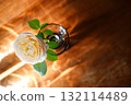 Yellow beautiful blooming rose in glass vase under window light on wooden table. 132114489