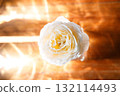 Yellow beautiful blooming rose in glass vase under window light on wooden table. 132114493