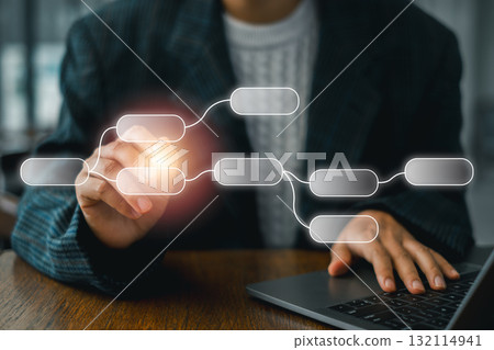 Business professional using a digital flowchart on a laptop to illustrate workflow and process management. 132114941