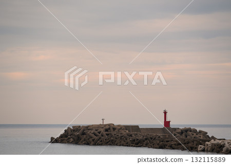 A red lighthouse standing in the pale twilight sky and sea 132115889