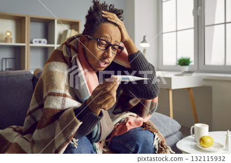 Young man sitting with thermometer feeling badly ill Young man sitting with thermometer feeling badly ill 132115932