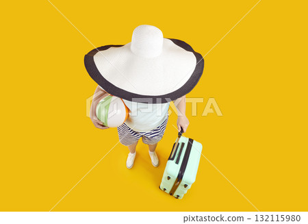 Funny high angle shot of woman with big sun hat, beach ball and suitcase on summer holiday Funny high angle shot of woman with big sun hat, beach ball and suitcase on summer holiday 132115980