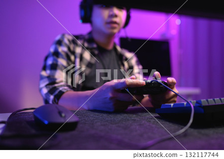 Closeup man playing video game at night with headset and neon RGB lighting Closeup man playing video game at night with headset and neon RGB lighting 132117744