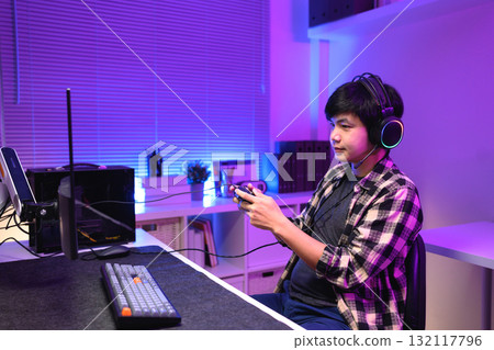 Focused gamer playing video game at night time Focused gamer playing video game at night time 132117796