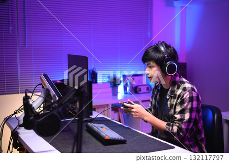 Focused gamer playing video game at night time 132117797