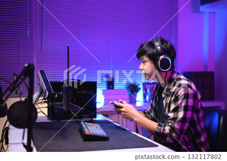 Focused gamer playing video game at night time 132117802