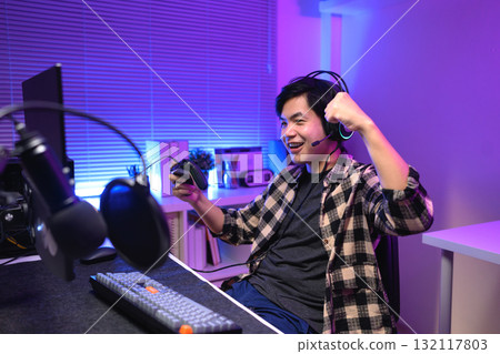 Excited gamer celebrating victory after winning video game at night, 132117803