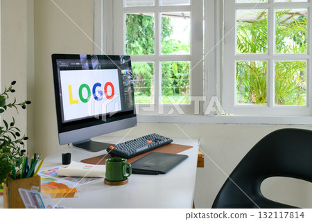 Creative woman designing logo sketches on notebook with color samples and tools in bright modern workspace 132117814
