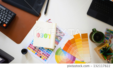 Top view of creative workspace with color palette, digital tablet, and notebook sketching logo design on clean white desk Top view of creative workspace with color palette, digital tablet, and notebook sketching logo design on clean white desk 132117822