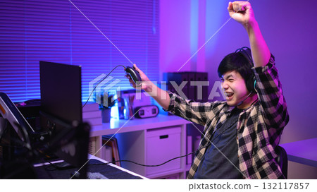 Excited gamer celebrating victory after winning video game at night, Excited gamer celebrating victory after winning video game at night, 132117857